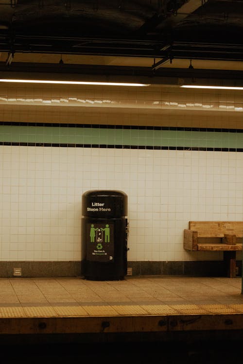 A subway station with a bench and a trash can