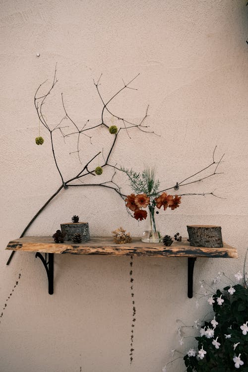 A shelf with flowers and branches on it