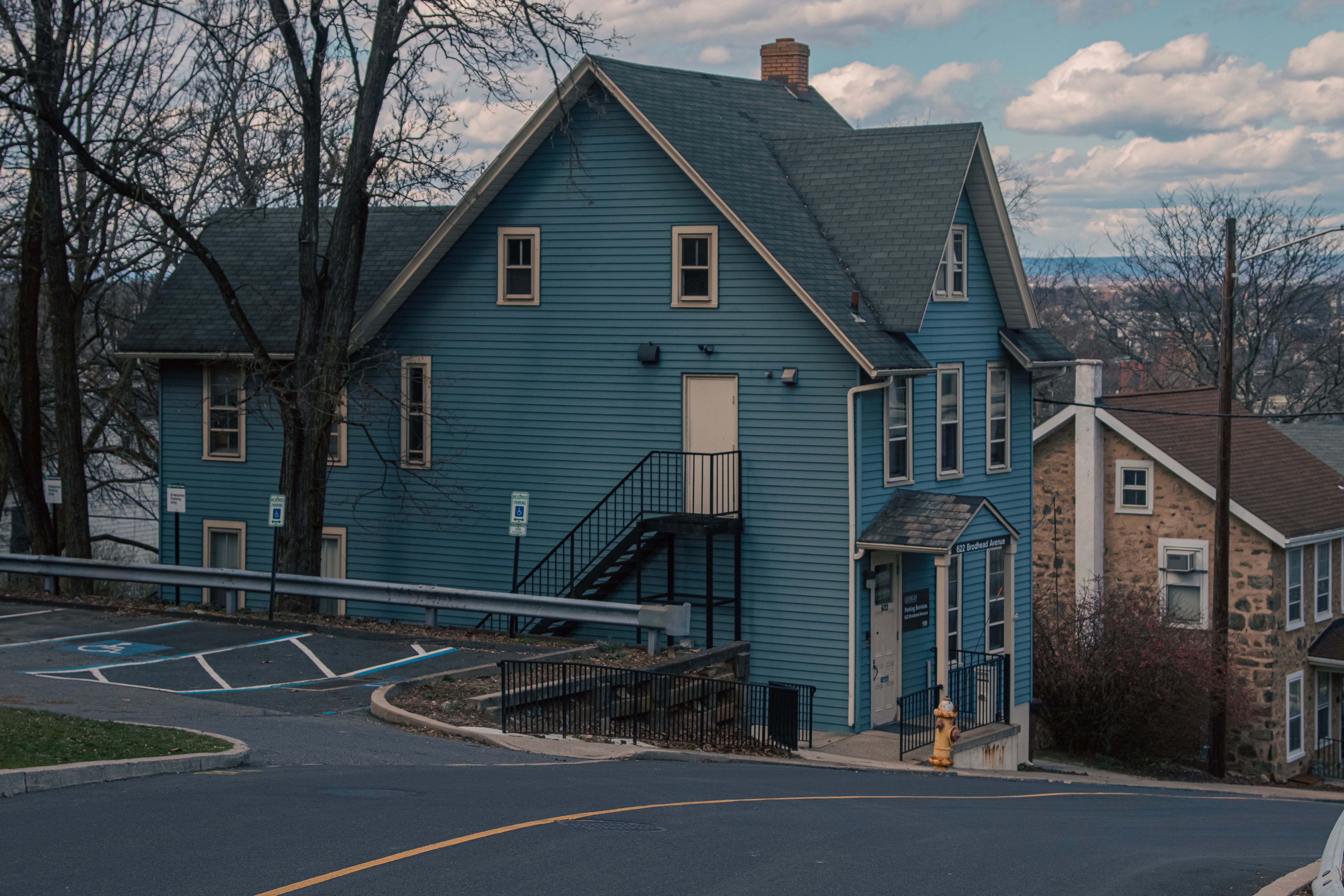 A quaint blue wooden house with a steep roof and scenic surroundings on a suburban street in Bethlehem, PA.