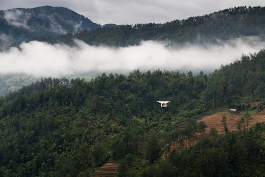 一架无人机飞越云雾缭绕、郁郁葱葱的青山，环境充满冒险气息