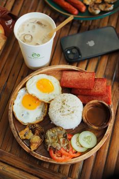 Delicious breakfast platter with fried eggs, rice, and iced coffee for a savory meal.