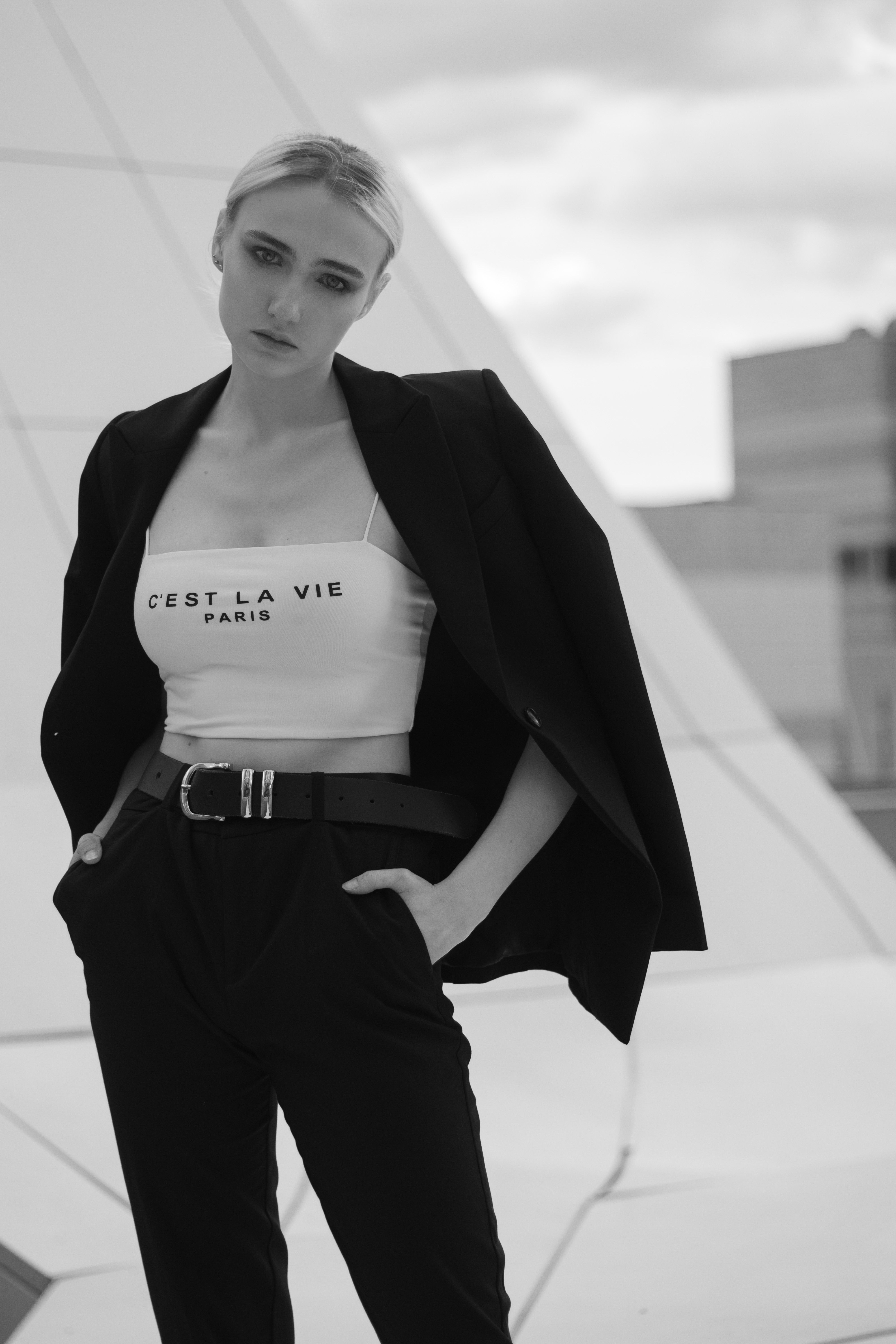 Stylish urban fashion portrait in black and white featuring a woman posing outdoors.