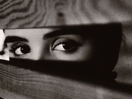 Free Captivating close-up of eyes peeking through a gap between wooden planks in black and white. Stock Photo