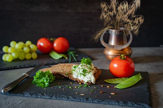 A creative food still life featuring bread, tomatoes, and cheese on a slate platter.