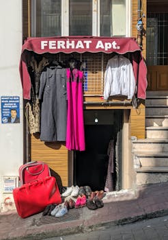 Colorful clothing and shoes displayed outside an apartment entrance in bright sunlight.