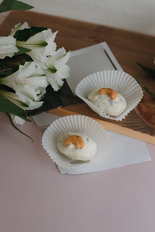 Free A white flower and two cupcakes on a pink table Stock Photo