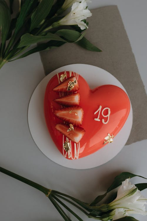 A heart shaped cake with strawberries and flowers