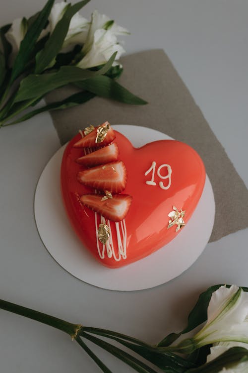 A red heart shaped cake with strawberries on it