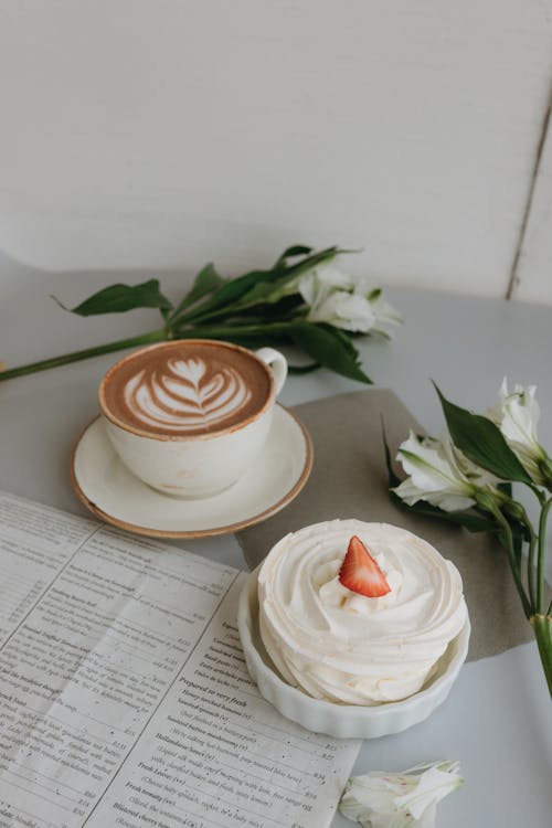 Free A cup of coffee and a cupcake on a newspaper Stock Photo