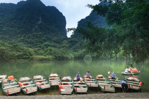 Free Boats lined up on a serene lake surrounded by lush green mountains, perfect for travel and nature lovers. Stock Photo