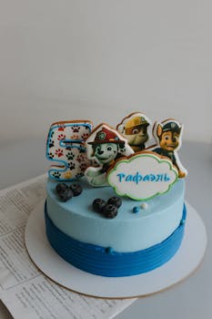 Blue themed children's birthday cake featuring popular cartoon characters and the number five decoration.