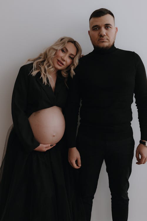 Free A pregnant woman and man in black standing next to each other Stock Photo