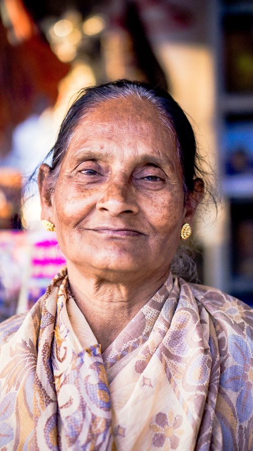 Free A portrait of a senior woman smiling warmly, wearing earrings and a patterned scarf. Stock Photo