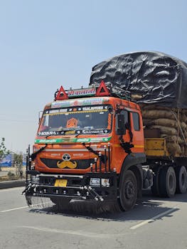 Colorful Indian cargo truck loaded with goods on highway, showcasing vibrant cultural decorations.