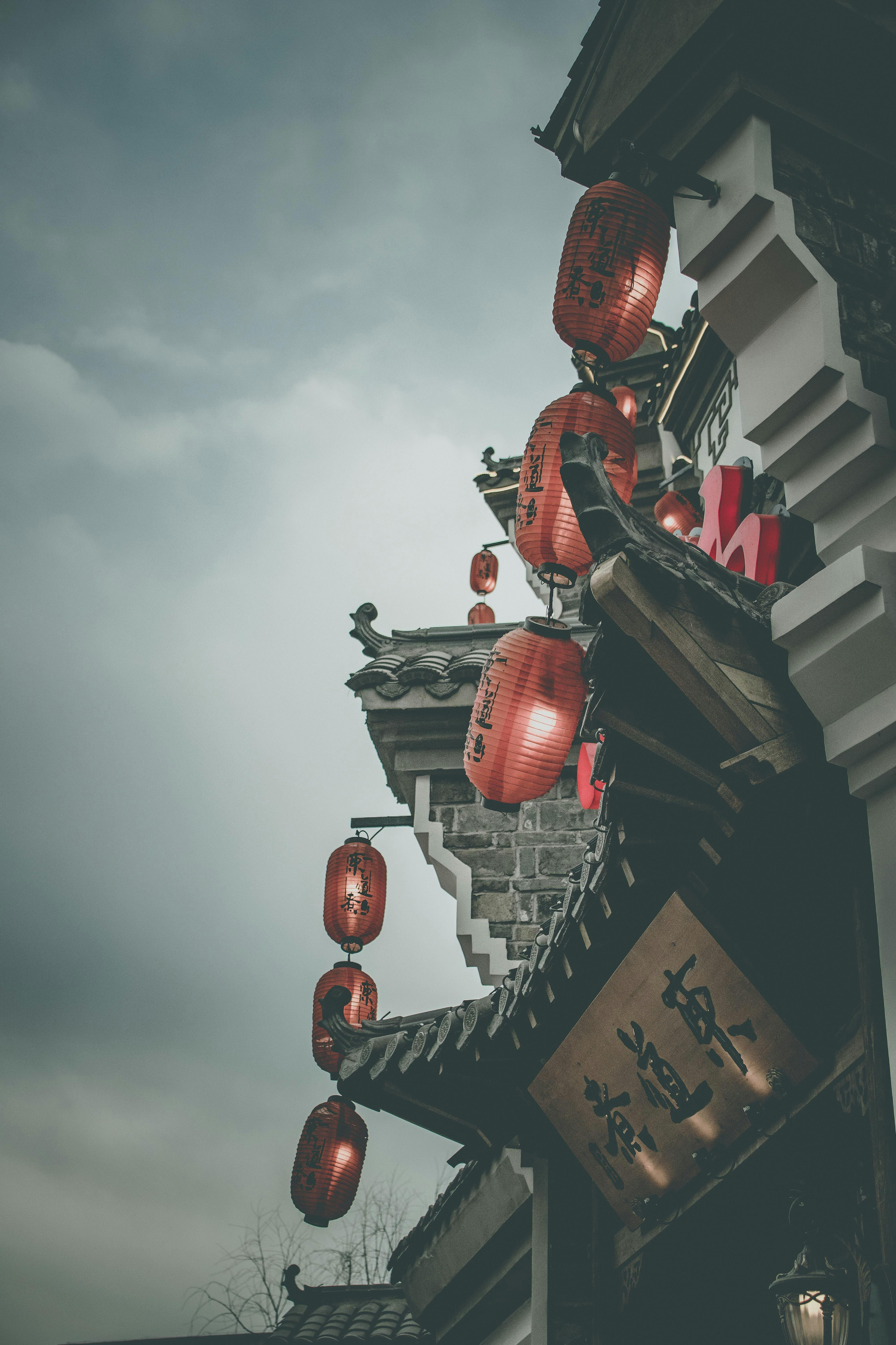 多云天空下，传统建筑上挂着红灯笼的街景显得格外大气