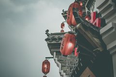 Atmospheric street view with red lanterns on a traditional building under a cloudy sky.