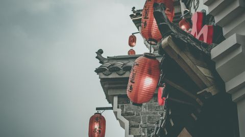Atmospheric street view with red lanterns on a traditional building under a cloudy sky.
