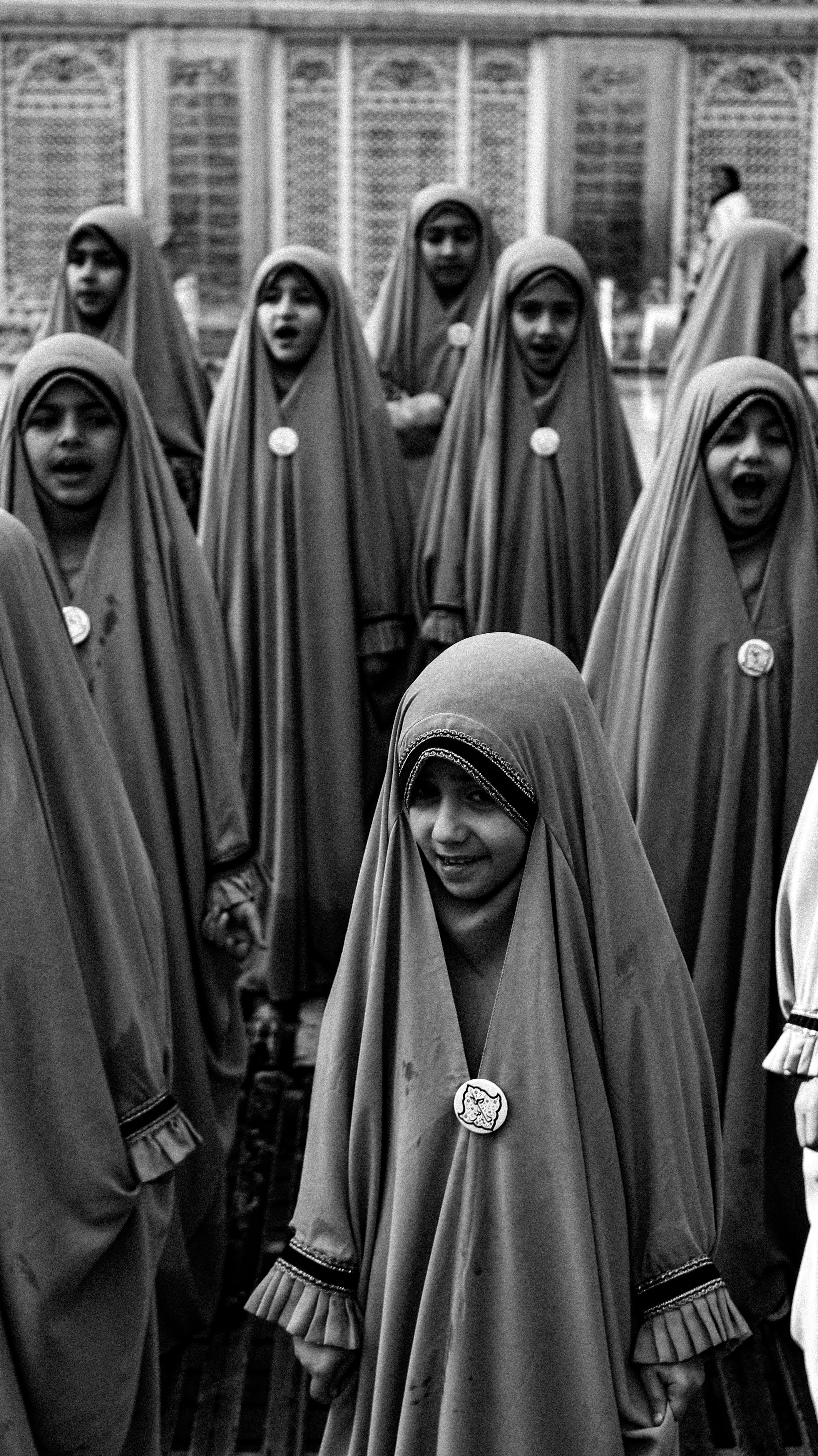 A group of children in costumes singing in a black and white choir performance.