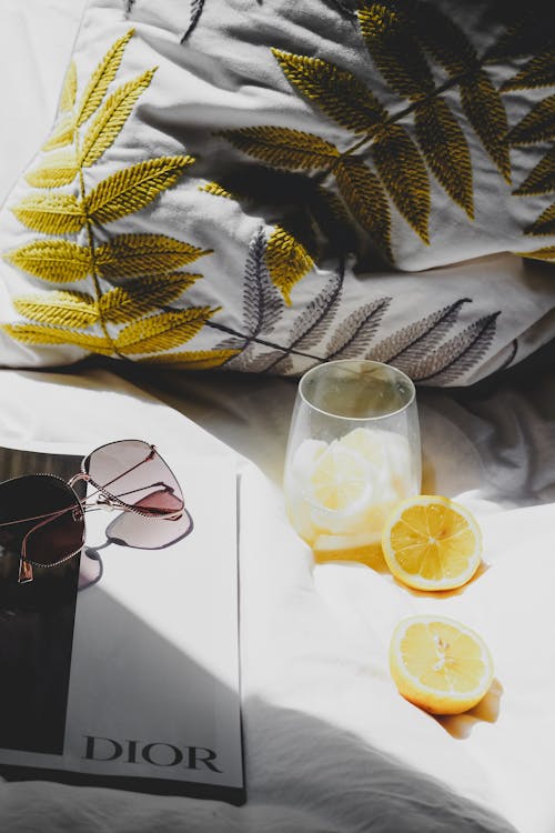 Free A book, sunglasses, lemon and glasses on a bed Stock Photo