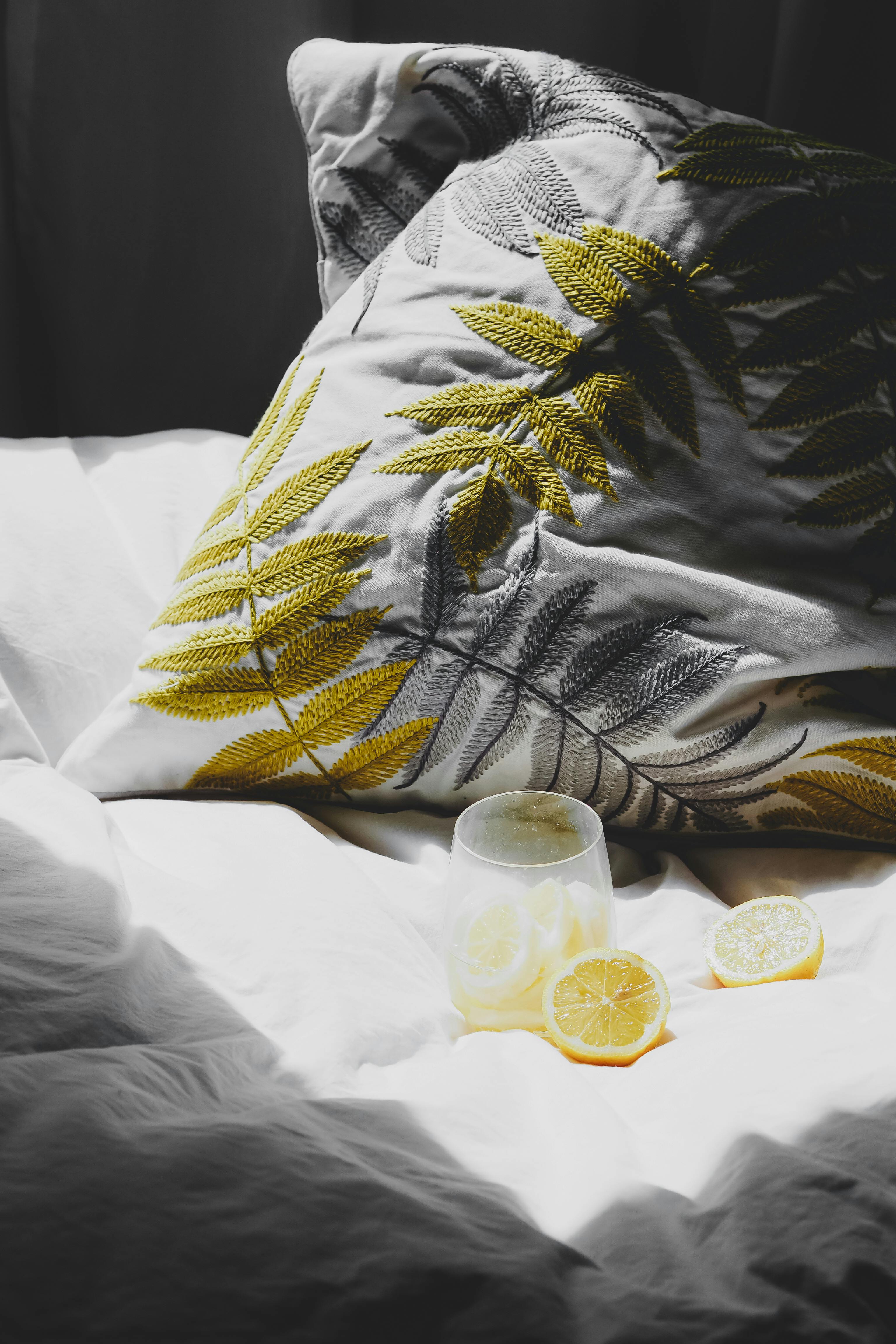 Cozy arrangement of lemons on bed with a pillow bathed in natural light, creating a serene vibe.