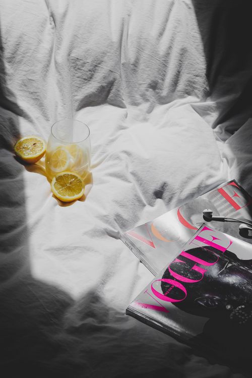 Free Flat lay of lemon slices and Vogue magazine on white linen, capturing a modern and chic aesthetic. Stock Photo