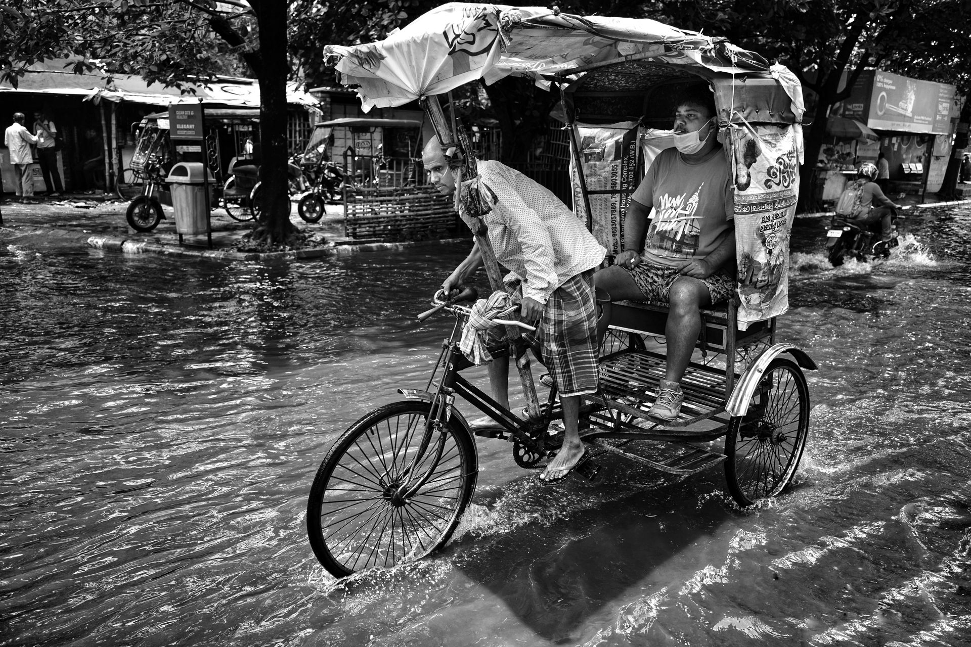 A rickshaw navigates flooded Kolkata streets during monsoon, showcasing urban resilience.