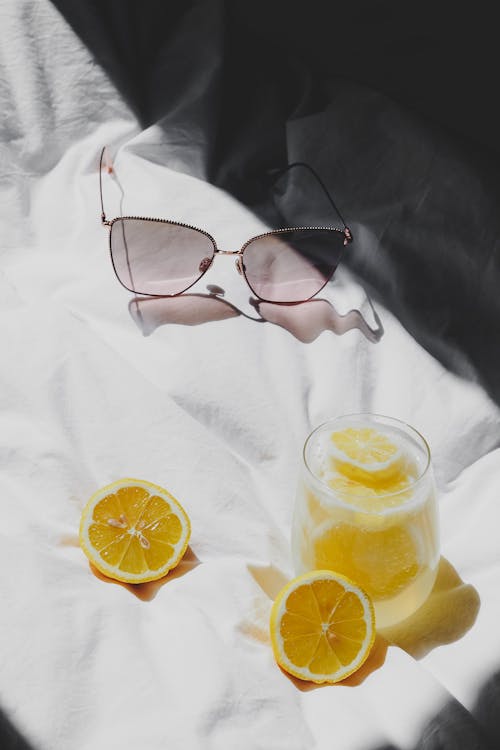 A glass of lemonade and sunglasses on a bed