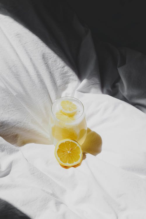 Free A glass of lemonade on a bed with a slice of lemon Stock Photo