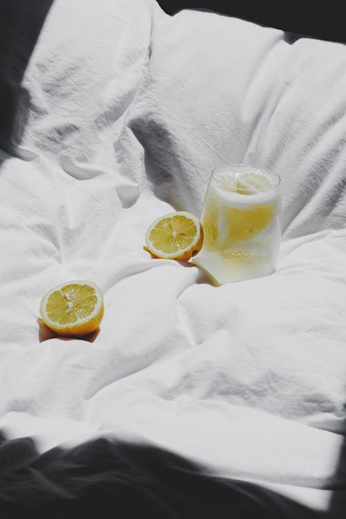 Free A glass of lemonade and a slice of lemon on a bed Stock Photo