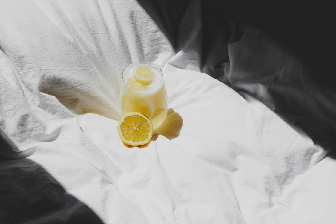 Free A lemon and glass of water on a bed Stock Photo