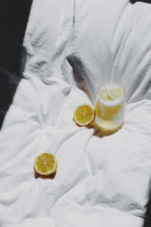 Free A lemon and glass of water on a bed Stock Photo