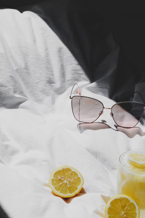 Free A pair of sunglasses and lemon slices on a bed Stock Photo