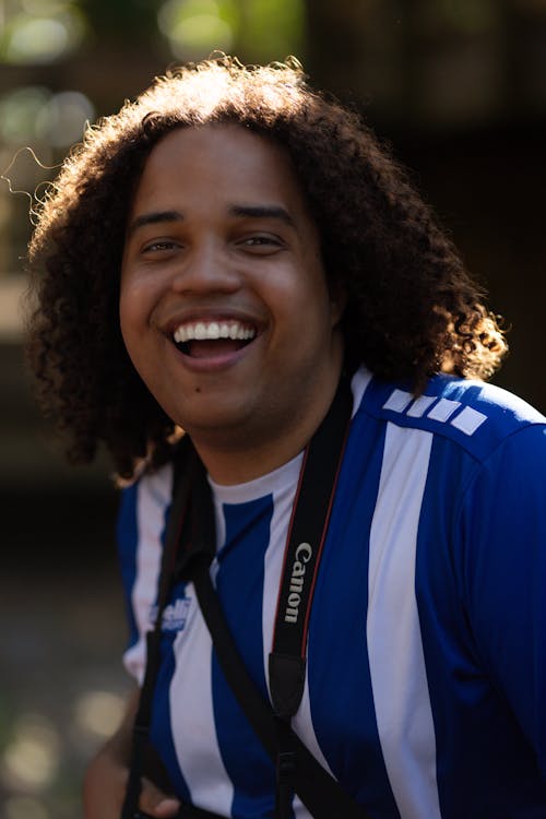 Free A man with curly hair smiling and holding a camera Stock Photo