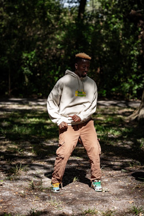 A man in a hoodie and pants standing in the woods