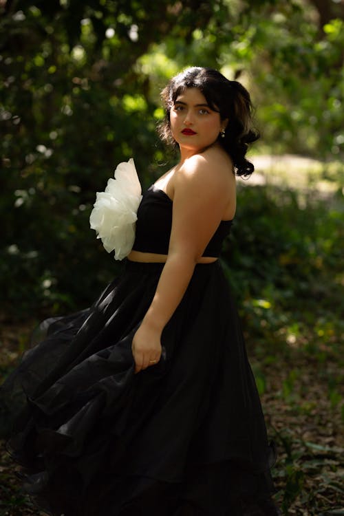 Young Brunette in a Black Dress Posing in a Park 