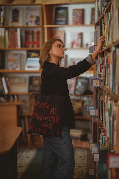 A woman is looking at books in a library