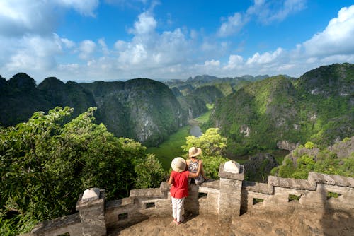 Couple Standing Beside Wall in Front of Mountain