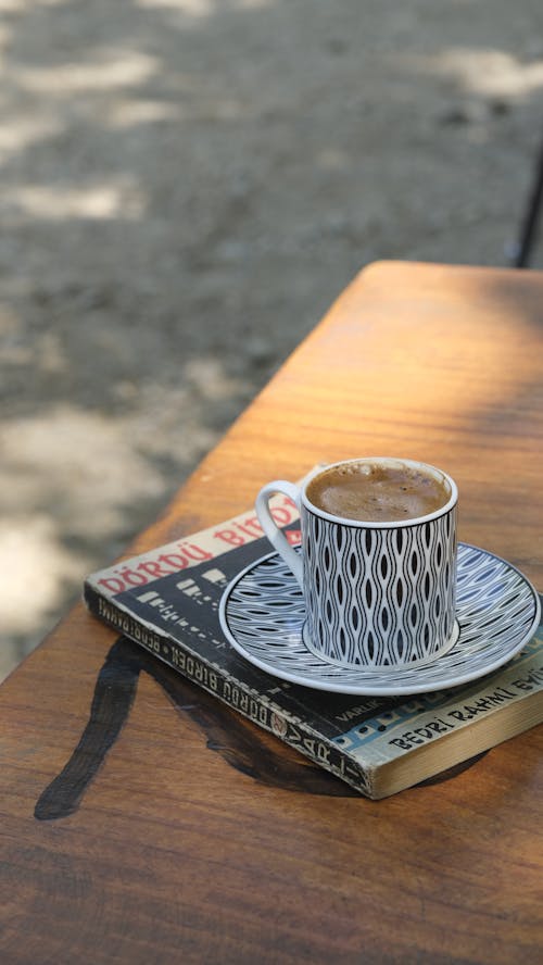 Free A cup of coffee sits on top of a book Stock Photo