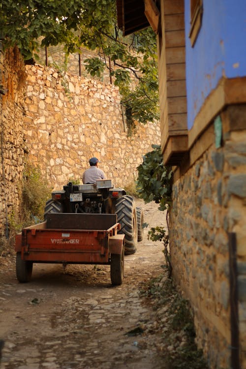 A man riding a tractor down a narrow alley