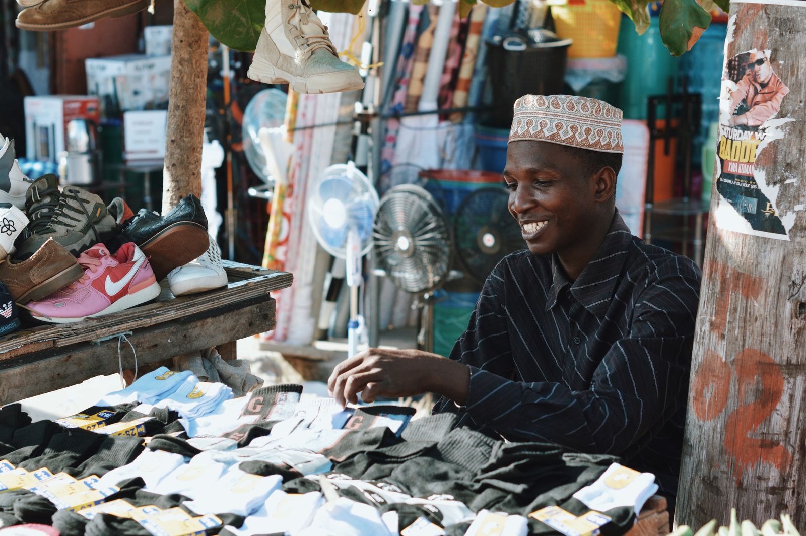 Vendeur souriant à son étal de marché, entouré de chaussures