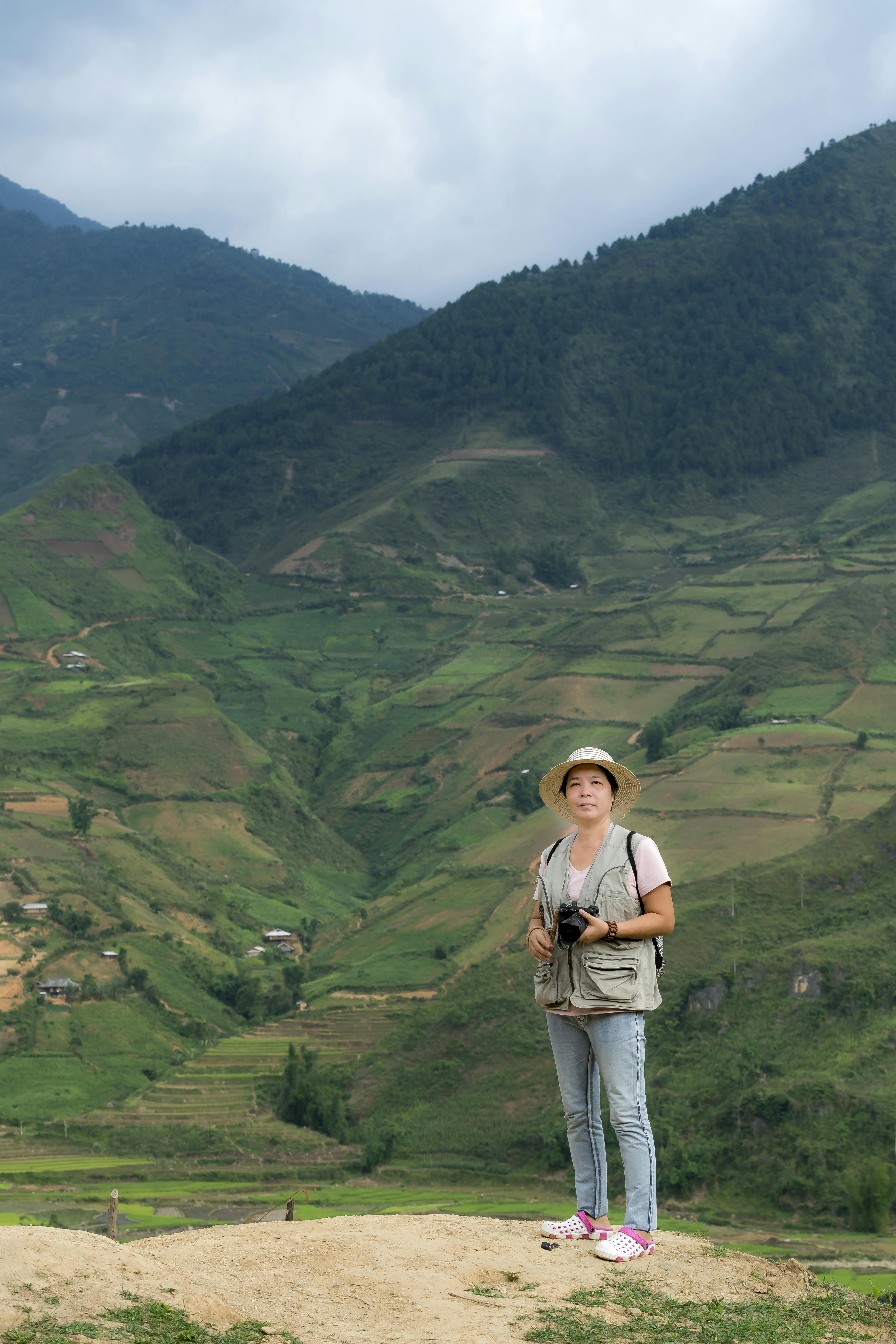 Woman Holding Camera In Front Of Green Mountain \u00b7 Free Stock Photo