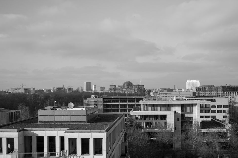 Black and white aerial view of Berlin's skyline featuring the iconic Reichstag building.