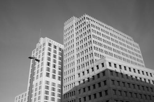 Free Black and white photo of a building with a plane flying by Stock Photo