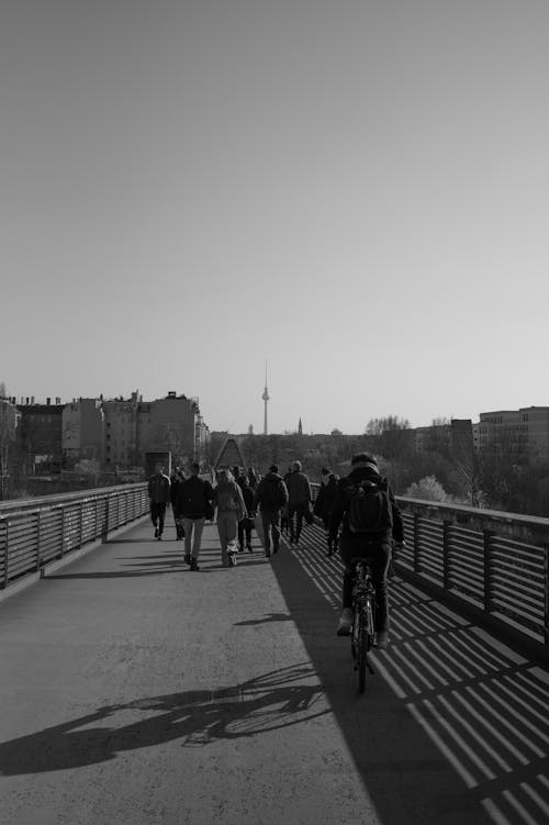 A black and white photo of people walking on a bridge