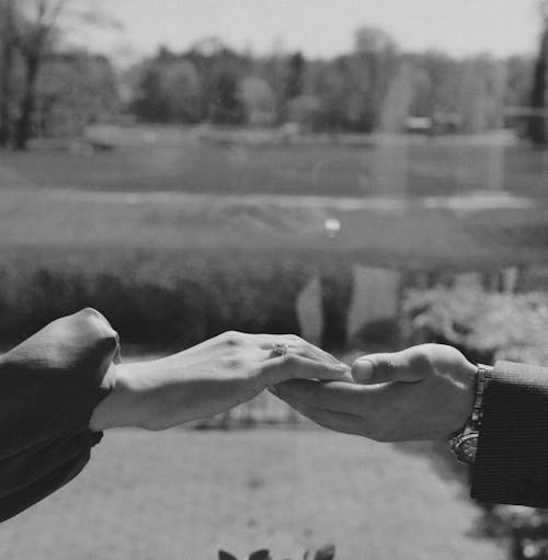 A black and white photo of two people holding hands