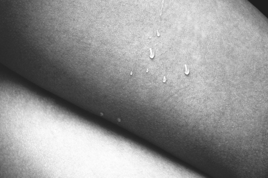 A conceptual black and white close-up photo of skin with water drops, highlighting texture and contrast.