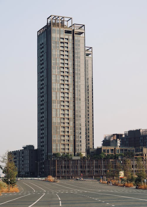 A tall building with a lot of windows in the middle of a parking lot