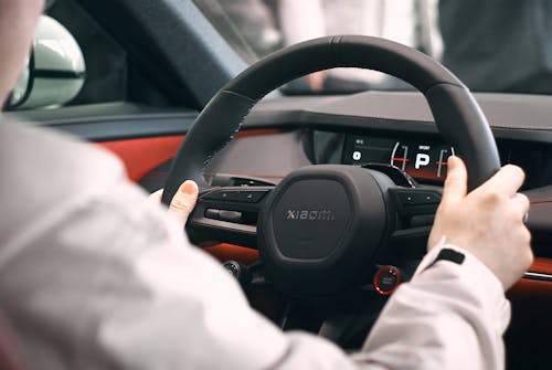 A man is driving a car with a steering wheel