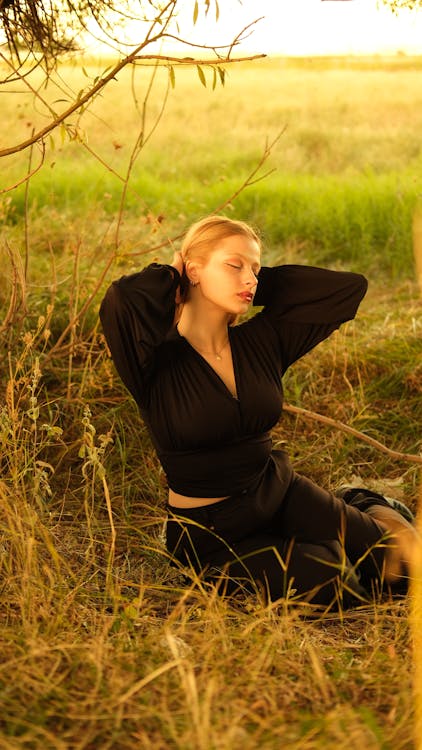 Free A woman in a black top sitting in the grass Stock Photo