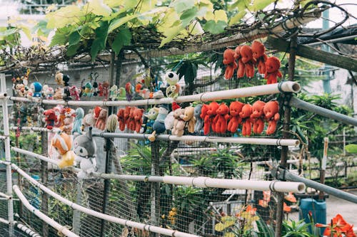 A fence with many stuffed animals hanging from it